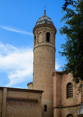 Obraz premium Tall tower of historic building under a clear sky with trees around in a city setting