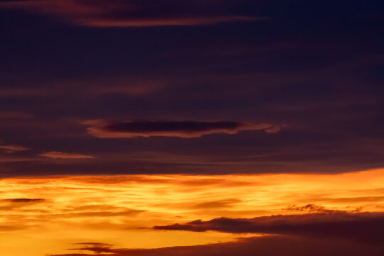 Dramatic sunset sky with golden clouds and deep purple twilight atmosphere for background