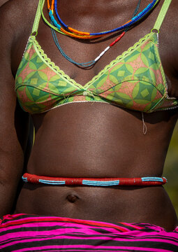Close-up of a woman's torso wearing a patterned bikini top and a beaded belt over a striped skirt, Cunene Province, Cahama, Angola