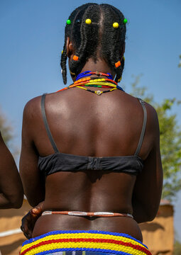 Rear view of a woman with beaded braids and layered necklaces above a striped beaded belt, Cunene Province, Cahama, Angola
