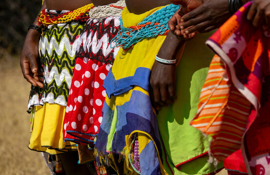 Close-up of several women's colorful patterned skirts and beaded waistbands standing side by side, Cunene Province, Cahama, Angola
