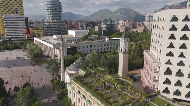 Aerial orbit around Et'hem Bey Mosque and Clock Tower in central Tirana, mountain in the distance, Albania
