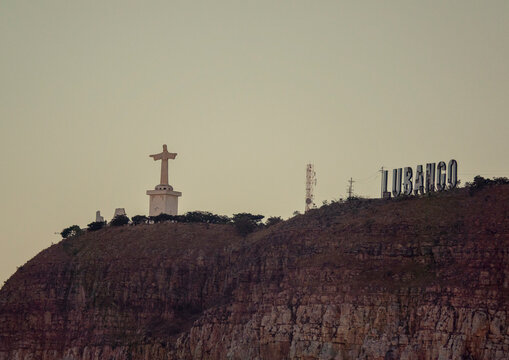 Distant view of the Cristo Rei statue and the LUBANGO sign standing together atop the cliff, Huila Province, Lubango, Angola