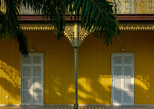 Cast-iron column beneath a palm frond flanked by two shuttered doors on the yellow facade of the Palacio de Ferro, Luanda Province, Luanda, Angola