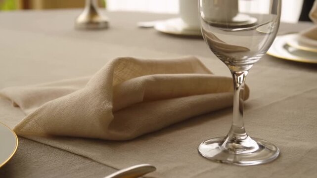 Formal dining table setting with folded napkin, empty wine glass, plates, and cutlery