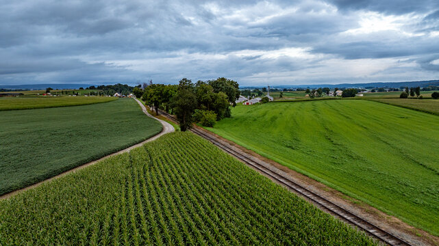 Expansive Rural Landscape Showcasing Farmland and Railway Under a Cloudy Sky in the Countryside