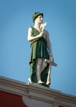 Close-up of a painted statue of Mercury wearing a winged helmet and holding a caduceus against a clear sky, Luanda Province, Luanda, Angola