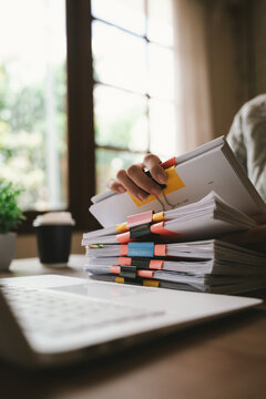 A close-up shot of an Asian woman handling a large volume of documents and files, dealing with organization, management, deadlines, workload, bureaucracy, and business responsibilities.