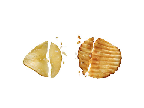 Broken potato chips and ridged crisps with salt. Crunchy snack pieces isolated on white background. Golden salty snacks macro photography