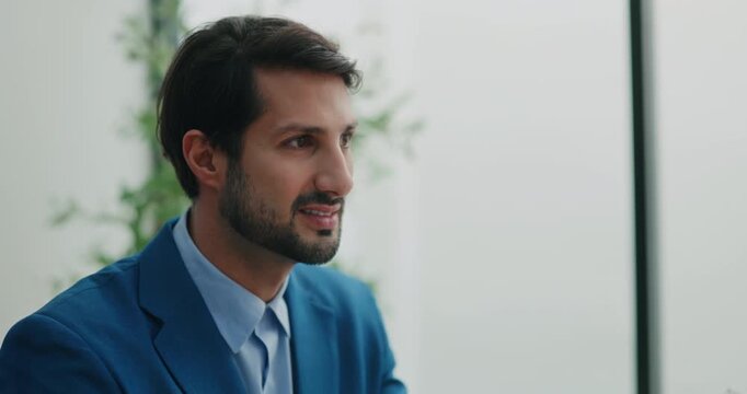 Portrait of Hispanic businessman in blue suit speaks at AI governance meeting in modern office. Manager looks away and expresses thought as discussing project