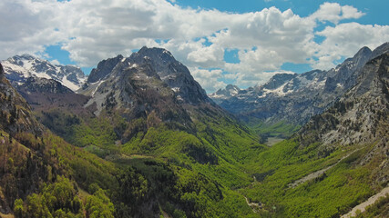 Fototapeta premium Rocky snow mountains and green valley aerial