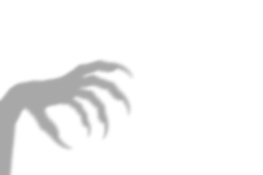 A creepy dark shadow of a monster hand with sharp claws reaching out from the side of the frame presented as isolated on transparent background