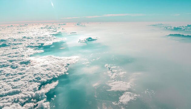 Above the Clouds: A breathtaking aerial view from an airplane window, showing a vast expanse of fluffy white clouds stretching towards the horizon under a clear blue sky.