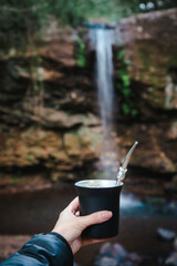 Tradicional infusión de yerba mate disfrutada en un entorno natural con cascada © Daniel