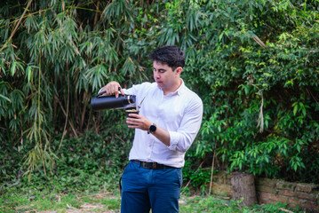 Hombre sosteniendo mate y termo frente a un fondo de plantas tropicales © Daniel