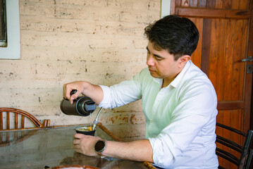 hombre con camisa blanca bebiendo mate mientras trabaja  © Daniel
