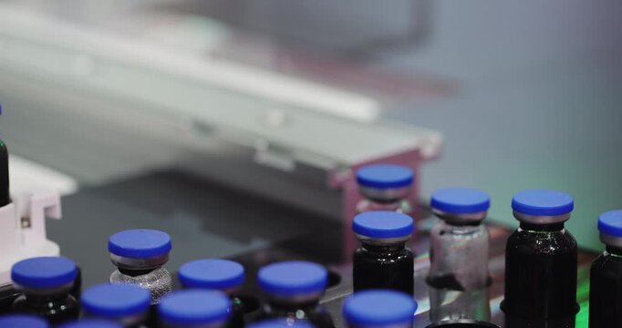 Robotic gripper sorts capped medicine vials into designated carrier containers. Automated system places each bottle accurately during pharmaceutical processing