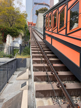 Orange funicular railway car on a steep hillside track in a city