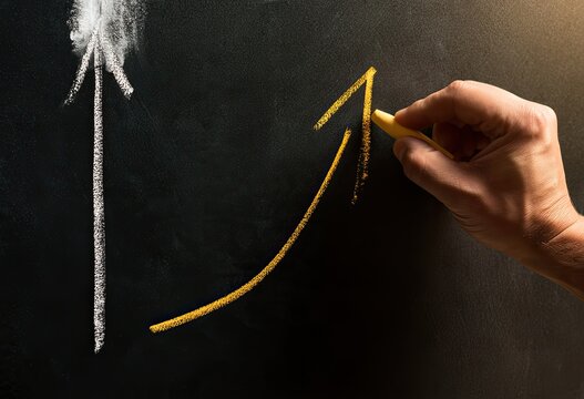 A hand draws an upward trending yellow arrow on a dark surface