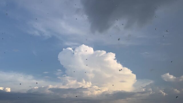 A sun shower with raindrops dripping from the roof edge beneath a bright sky.