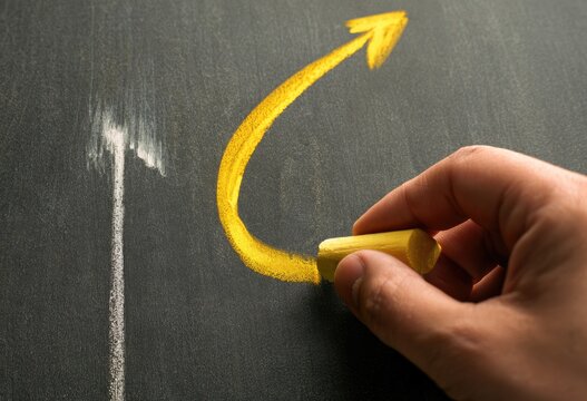 Yellow chalk draws curved arrow and line on a dark surface