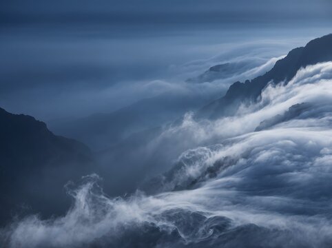 Ethereal Mist Rolling Over Rugged Mountain Peaks at Blue Twilight With Low Clouds and Fog