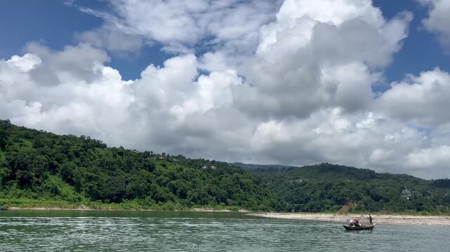 Jaflong Sylhet Small boats navigate a calm river under fluffy white clouds and lush green forest mountain