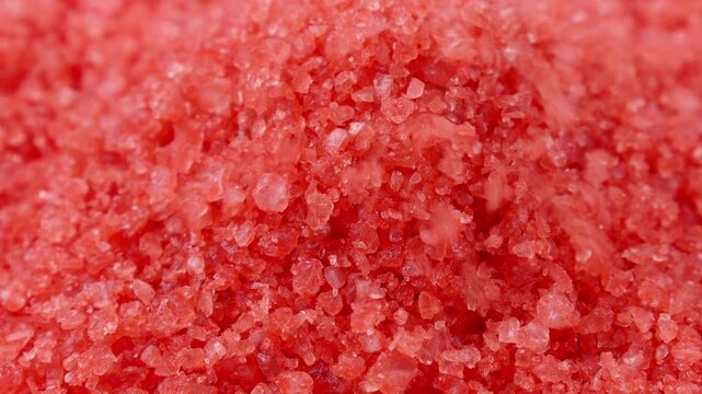 Red bath salt crystals falling down close up