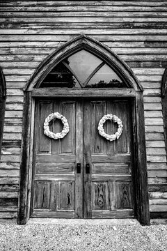 Rustic wooden doors of a historic sanctuary on Pelee Island, Ontario, adorned with ornamental wreaths.