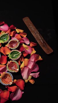 Burning Diya Lamps and Rose Petals in a Diwali Arrangement