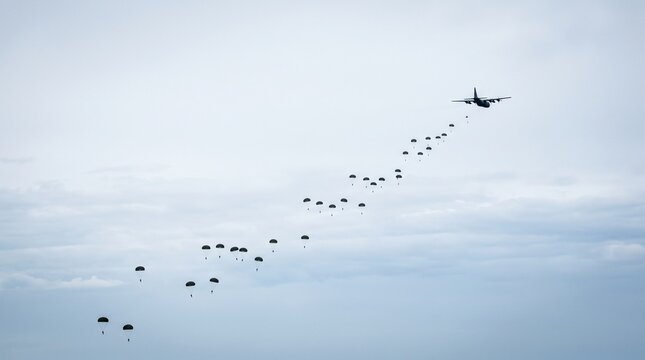 Military Transport Plane Deploys Paratroopers in Formation Over Cloudy Sky