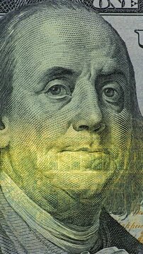 Benjamin Franklin dollar bill close up. Benjamin Franklin on dollar bill appears in real camera recording. Close up view holds on printed currency as changing light reveals paper texture.