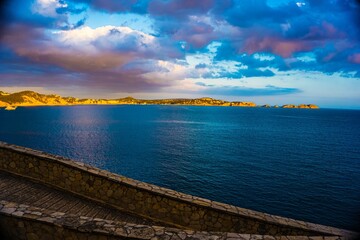 Fototapeta premium Dramatic sunset over a coastal landscape with blue ocean