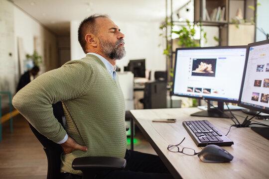 Office worker with lower back pain at computer desk