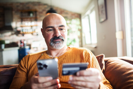 Middle-aged man making mobile payment at home