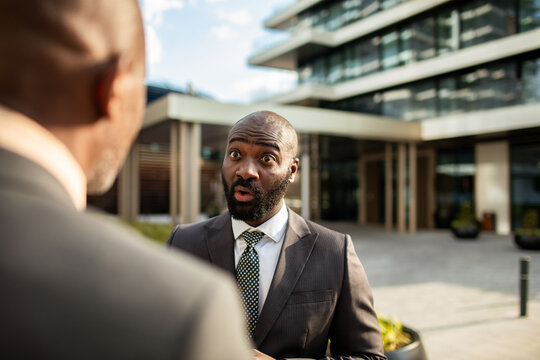 Businessman reacting in surprise during outdoor office conversation