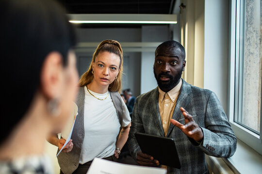 Coworkers discussing project with colleague in modern office