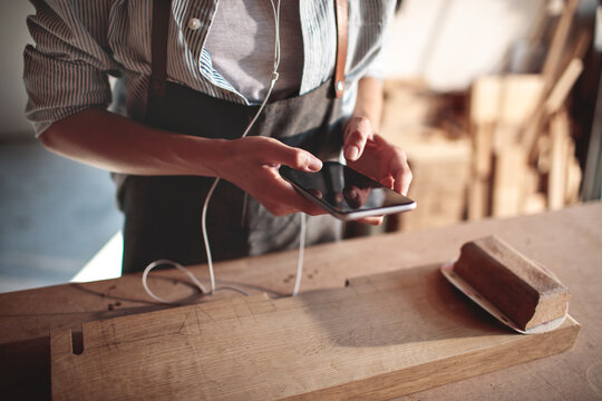 Carpenter using smartphone in woodworking workshop