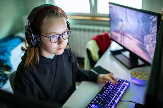 Young gamer with headset playing pc game at home desk