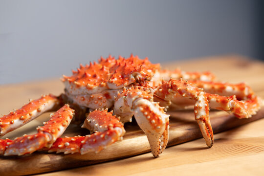 Close-up of cooked king crab legs on a wooden board, shell texture detail, appetizing seafood closeup, culinary photography.