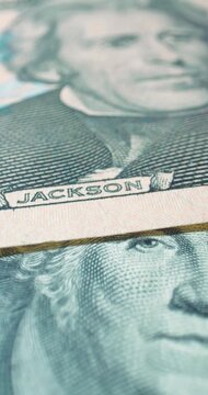 Close view of stacked dollar bills. Real camera view of US dollar banknotes fills frame with printed portraits and security details. 
