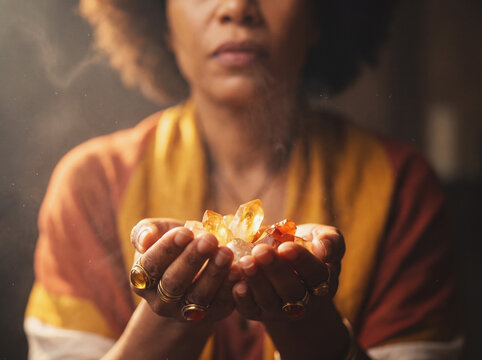 Woman holding glowing citrine and carnelian crystals in cupped hands, mystical light