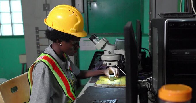 Quality inspector examining small metal component under stereo microscope in factory lab