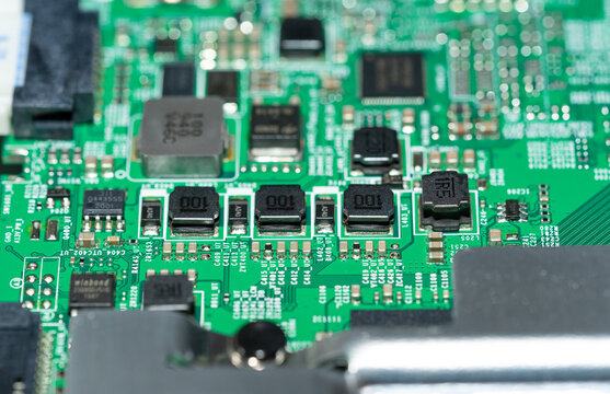 Straight macro shot of black SMD inductors and chip resistors on green PCB