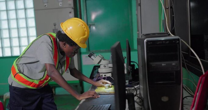Quality inspector examining small metal component under stereo microscope in factory lab