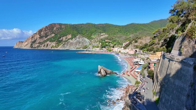 Beachfront village beside turquoise sea and rocky headland.  Monterosso al Mare, Italy