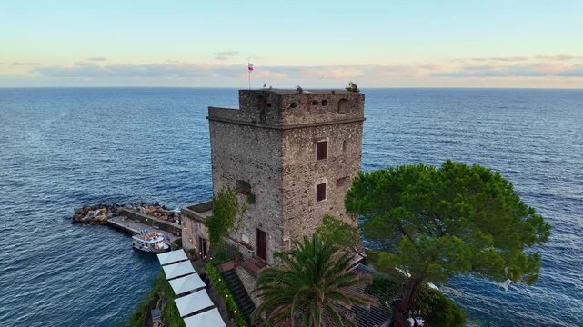 Stone coastal tower beside small pier and moored boats.  Monterosso al Mare, Italy