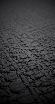 Dark textured surface in real footage fills frame with soft spotlight and deep shadow.