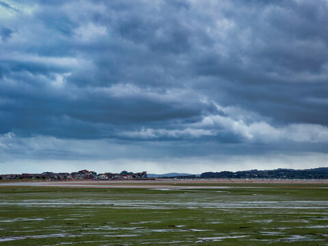 Low tide estuary mudflats under a dramatic stormy dark sky