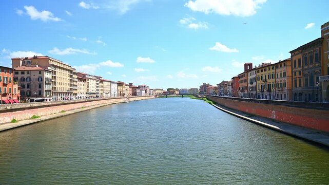 Riverside buildings lining a calm river with brick embankments. Pisa, Italy